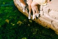 Legs of a man and a woman in sneakers over the water sitting on the edge of the pier, close-up Royalty Free Stock Photo