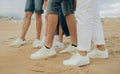 Legs of millennial diverse people in white sneakers on beach, outdoor, cropped. Active game, picnic Royalty Free Stock Photo