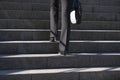 Legs of modern businesswoman woman in black pants walking up the stairs to the office holding briefcase. Royalty Free Stock Photo