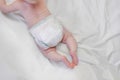 The legs of a newborn baby. Baby pink baby legs that learn to crawl in a crib with a white sheet. a tiny unrecognizable girl moves Royalty Free Stock Photo