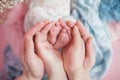 Legs of a newborn baby, a child in the hands of parents, parental love