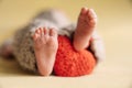 Legs of a newborn. Baby feet with a crochet heart. The tiny foot of a newborn in soft selective focus. Royalty Free Stock Photo