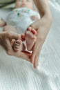 Legs newborn baby and Mama`s arms heart Royalty Free Stock Photo