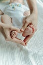 Legs newborn baby and Mama`s arms heart Royalty Free Stock Photo