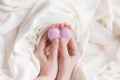 Legs of a newborn baby stick out from under the heart that mom holds on a white diaper, macro photo of the fingers Royalty Free Stock Photo