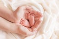 Legs of a newborn child in the palms of mother, mother`s day, mother`s universe