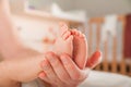 Legs of a newborn in hands closeup. Baby`s feet and copy space. Infant care and colic. Royalty Free Stock Photo