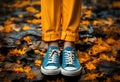 Legs in old sneakers standing on ground with carpet of yellow leaves in fall. Autumn season concept Royalty Free Stock Photo