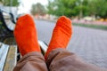 Legs in orange socks on a bench outside