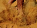Legs of a person while walking on field ground with thick layer of dirt dust raised