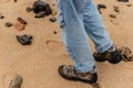 Legs of a person wearing pants and shoes against the beach sand Royalty Free Stock Photo