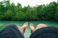 Legs point of view of alone male who sit and sleep over the water surround mangrove forest