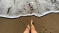 Legs from point of view in front of sea waves on the shore Royalty Free Stock Photo