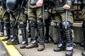 Legs of a policemen in protective ammunition and a green uniform. Knee pads, helmets, batons, boots