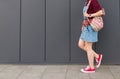 Legs in red sneakers, backpack and denim dresses go down the ground against the background of a dark wall