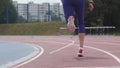 Legs in red snikers of a young woman athlete who starts running at the city athletics track during training in slow