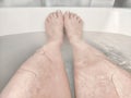 Legs during Relaxing Bath Time in a Tranquil Home Bathroom. Person enjoys a moment of relaxation, with their legs