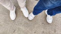 Legs in sneakers and jeans on asphalt, top view. The concept of tourism, travel, trips, tourists, convenience