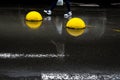 Yellow concrete hemispheres on wet asphalt.