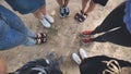 Legs and sneakers of teenage boys and girls standing in half circle on the sand. Royalty Free Stock Photo