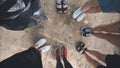 Legs and sneakers of teenage boys and girls standing in half circle on the sand. Royalty Free Stock Photo