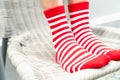 Legs in socks red colors alternate, white side stand on white chair. Royalty Free Stock Photo