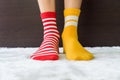 Legs in socks two colors alternate, Red and yellow side stand on white fabric floor. Royalty Free Stock Photo