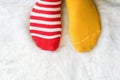 Legs in socks two colors alternate, Red and yellow side stand on white fabric floor. Royalty Free Stock Photo