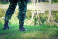 Legs of soldier standing near river, close up view, Black boots
