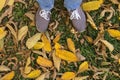 Legs in sport shoes standing on yellow autumn dry leaves in grass. Feet in shoes walking in fall nature