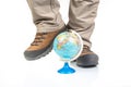 Legs of a tourist in trekking boots for hiking next to a model of a globe on a white background. Travel and Hiking Equipment