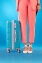 Legs, travel and a person with a suitcase on a blue background for a vacation or adventure. Ready, airport or a woman