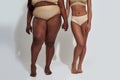 Legs of two african american women in underwear with different body size holding each other hands, standing together Royalty Free Stock Photo