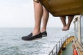 The legs of two men sitting on the upper deck of a ship during a boattrip at the open sea in the summer, one bare feeted, the