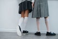 Legs of two schoolgirls stadning next to a wall close to one another. Royalty Free Stock Photo