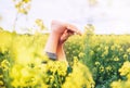 Legs up of happy female lying in deep yellow flowers meadow. Happiness in nature concept image