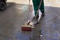 Legs of a urban cleaning worker cleaning the floor wet from the rain at the fair in Sao Joaquim