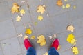 Legs urban grunge background with asphalt with fallen leaves Conceptual image of foot in boots on the street of the autumn city