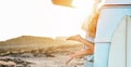 Legs view of happy surfer girl inside minivan at sunset - Young woman having fun on summer vacation - Travel,sport and nature Royalty Free Stock Photo