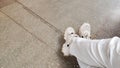 Legs in white jeans and white sneakers on gray pavement tiles. The concept of travel, traveler, buying new shoes Royalty Free Stock Photo