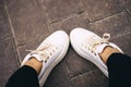 Legs in white sneakers with gold laces. Relaxation. Shopping concept. Fitness concept