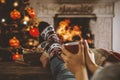 Wooden table with legs in christmas socks, a mug in woman`s handsand, space for your decoration, products and text. Royalty Free Stock Photo