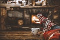 Wooden table with legs in christmas socks, a mug in woman`s handsand, space for your decoration, products and text. Royalty Free Stock Photo