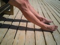 Legs of a woman sitting on a bench taking a sunbath