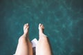 Legs of woman sitting on teak wood swim platform on blue sea Royalty Free Stock Photo