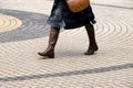 Legs of a woman walking on concentric circles pavement