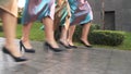 The legs of women in black shoes synchronously walking down the street. Beautiful legs of women walking in a row