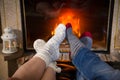 Legs in woolen socks stretched out heat up near fireplace Royalty Free Stock Photo