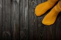 Legs yellow knitted woolen socks on wooden dark background.