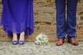 Legs of young dressy women and man wearing blue in front of the brick wall